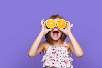 Happy little girl in summer dress holding an orange on a yellow background with space for text.