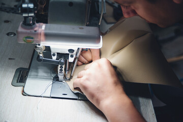 Working process of leather craftsman. Tanner sews leather on a special sewing machine, close up.