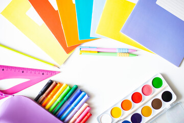 Back to school concept. Bright colorful school supplies (notebooks, pens, watercolor paints, markers, ruler, pencil box) on a white background. Flat lay, top view.