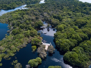 Fototapeta na wymiar Drone aerial view of forest trees, small houses and boats in the biggest flood of the Negro river history in the Amazon rainforest. Concept of environment, ecology, climate change, global warming.