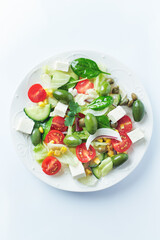 Healthy Salad with Feta Cheese, Green Olives, Baby Spinach, Cucumber, Cherry Tomatoes and Capers. Bright background. Top view. 