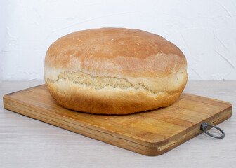Round fresh homemade bread on a wooden board.