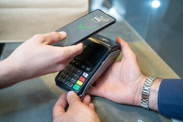 Contact less payment via smartphone. Conclusion of a money transaction through modern POS payment...