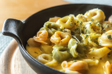 Fresh tortellini pasta served with creamy curry sauce in a pan