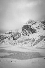 Obraz premium Monochrome Czarny Staw Gąsienicowy Lake view, High Tatra Mountains, Poland. Ice on the pond, snow on the rocks. Selective focus on Kościelec Peak, blurred background.
