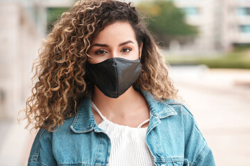 Latin woman wearing a face mask while standing outdoors.