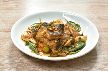 spicy slice stingray fish with eggplant and basil leaf in curry sauce on plate