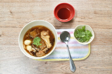 braised fish maw with bamboo shoot topping slice chicken and boiled egg quill in red gravy soup on plate