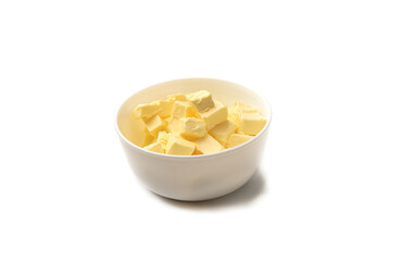 Diced butter in a white cup over a white background.