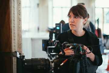 Female director of photography with a camera on a movie set. Professional videographer on the set...