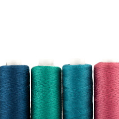 Close-up of spools of colored thread on a white background.