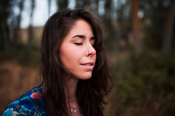 Fototapeta premium Outdoor portrait of a beautiful brunette woman wearing a dress in the forest