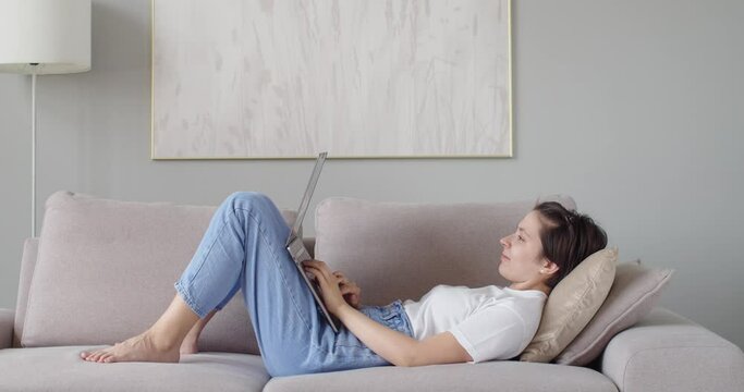 Side view of female student doing homework online on pc laptop copy space. Happy woman girl using notebook communicating with friends slow motion. Remote work home education leisure time