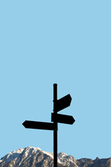 Mountains with black hiking trailhead post showing directions with copy space and blue sky solid background. Concept of travel, hiking and mountaineering.