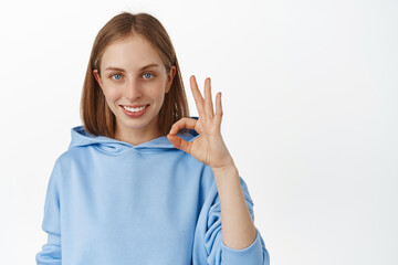 Image of young confident caucasian woman showing ok, okay zero sign and smiling assertive, happy...