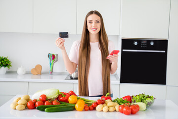 Photo portrait young woman cooking keeping credit card smartphone waiting delivery