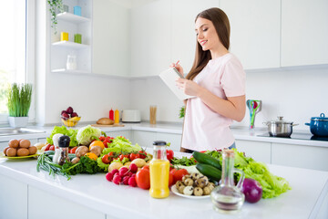 Obraz na płótnie Canvas Profile side view portrait of attractive cheery long-haired girl cooking fresh yummy homemade salad writing in light white home kitchen indoors
