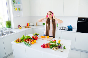 Portrait of attractive dreamy long-haired girl cooking fresh vegs vitamin salad pout lips at home light white kitchen indoors