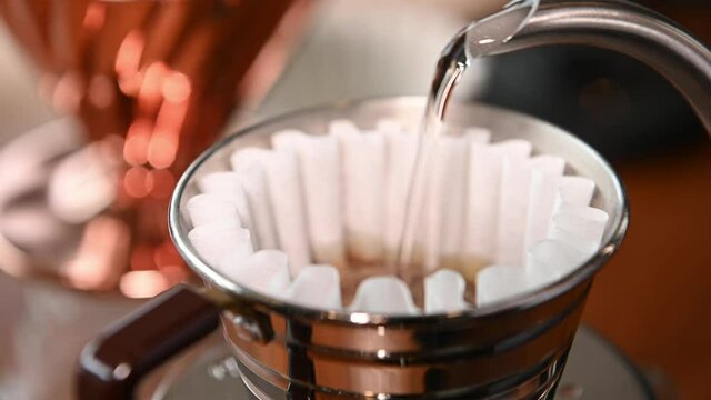 The barista is brewing coffee with traditional drip brewing equipment.