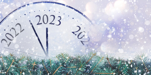 Clock counting last moments to New 2023 Year and beautiful fir branches, banner design. Bokeh effect