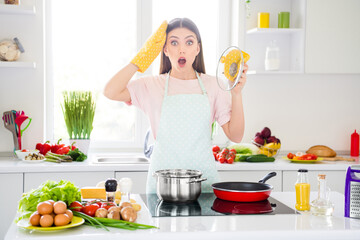 Portrait of attractive astonished girl preparing weight loss useful dinner boiling at home light white kitchen indoors