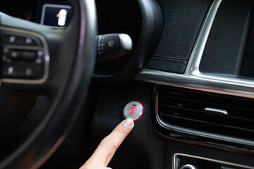 Fototapeta premium Close up of finger pressing the start/stop engine button on car.