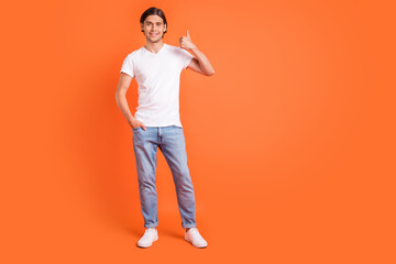 Fototapeta na wymiar Full length photo of happy positive young man hold hands show thumb up isolated on orange color background