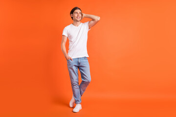 Fototapeta na wymiar Full body photo of cheerful young happy positive man look empty space imagine isolated on orange color background