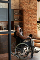 Vertical side view portrait of contemporary tattooed woman with disability using laptop while working from home