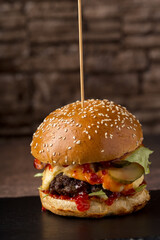 Burger with meat on black stone stand