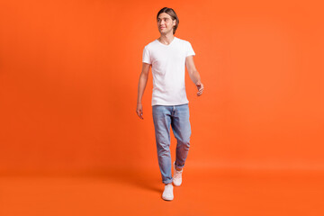 Fototapeta na wymiar Full body photo of cheerful young dreamy man look empty space good mood isolated on orange color background