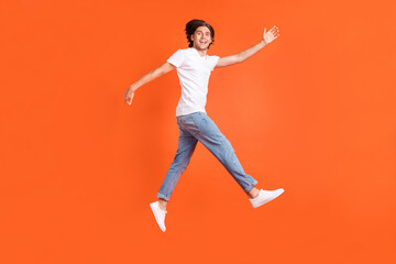 Fototapeta na wymiar Full size photo of happy cheerful positive man jump up go empty space sale isolated on orange color background