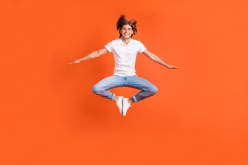Fototapeta na wymiar Full body photo of happy positive cheerful man jump up good mood active isolated on orange color background