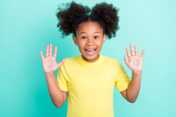Photo of funny brunet little girl hands up wear yellow t-shirt isolated on teal color background