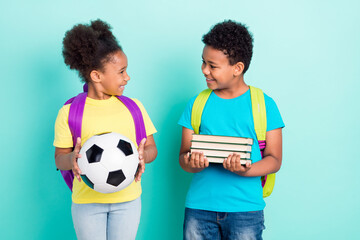 Portrait of two nice cheerful friends friendship holding book ball things isolated over bright teal turquoise color background