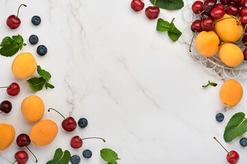 Fresh apricots, red cherry and blackberry on white marble background. Vegetarian, weight loss, clean and healthy eating concept. Top view. Copy space.