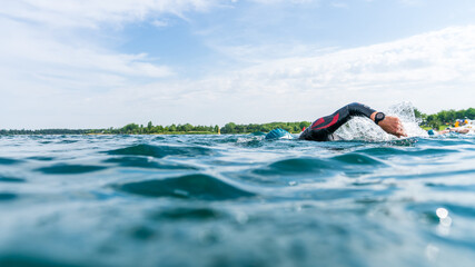 Triathlete in a wetsuit swims in a lake at a triathlon competition