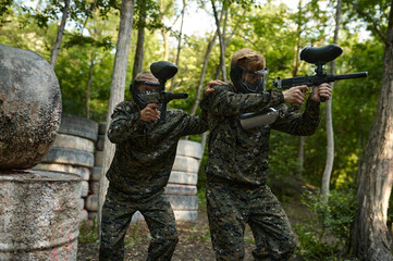 Fototapeta premium Paintball players in uniform and masks in forest