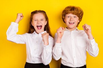 Photo of two best friends schoolchildren raise fist in victory celebrate 1-september isolated on yellow color background