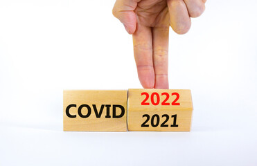 Symbol of covid-19 pandemic in 2022. Doctor turns a wooden cube and changes words 'covid 2021' to 'covid 2022'. Beautiful white background, copy space. Medical, covid-19 pandemic in 2022 concept.