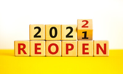 2022 reopen new year symbol. Turned a wooden cube and changed words 'Reopen 2021' to 'Reopen 2022'. Beautiful white background, copy space. Business, 2022 reopen new year concept.