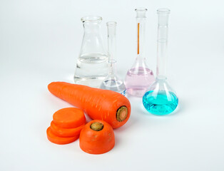 Fresh carrots with science test tubes on white background.                         