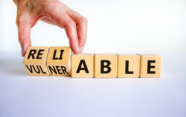 Vulnerable or reliable symbol. Businessman turns wooden cubes and changes the word Vulnerable to...