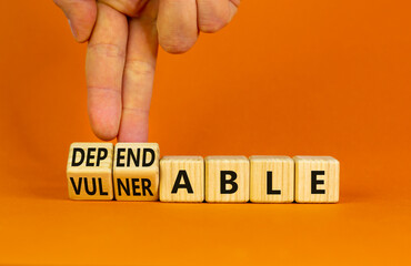 Vulnerable or dependable symbol. Businessman turns wooden cubes and changes the word Vulnerable to...