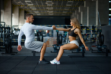 Sportive couple doing push-ups, training in gym