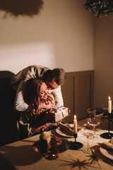 A festive romantic candlelit dinner in the evening. A happy man hugs and gives a gift box to a beloved woman on a Christmas holiday at home, a selective focus