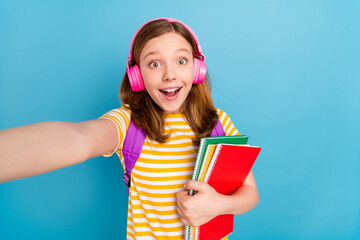 Photo of excited astonished schoolchild hold notebook recording video isolated on blue color background