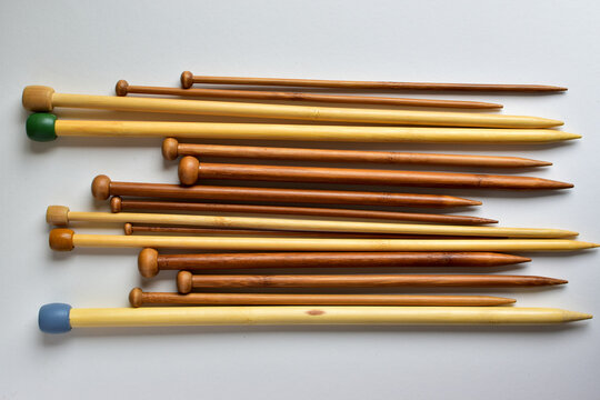 wooden knitting needles of various sizes on white background 