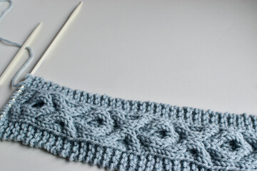 blue cable stitch knitting pattern on white needles with copy space for text 