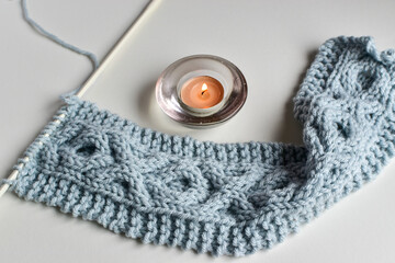 blue cable stitch knitting pattern on white needles with copy space for text 